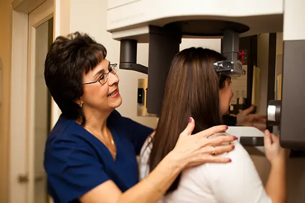 A dental assistant helping a patient get a 3D x-ray.