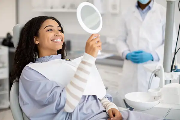 A patient checking out her smile in mirror after her treatment at East Portland Dentistry