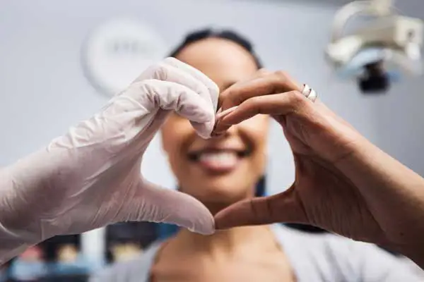 A patient and hygienist holding heart around patient's smile at East Portland Dentistry 