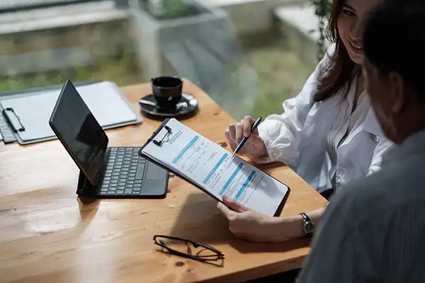 A dentist helping her patient fill out insurance paperwork on a clipboard