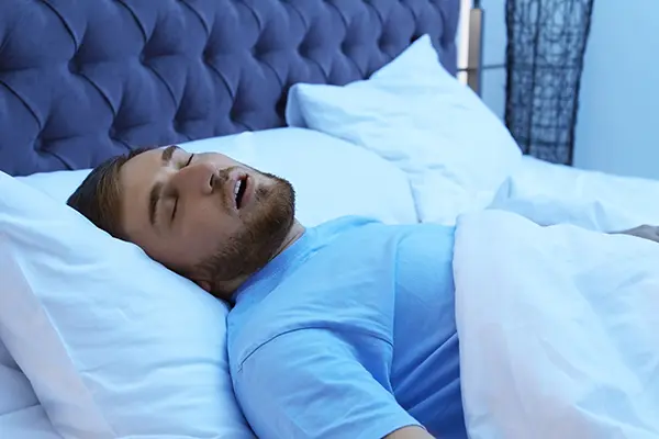 White man with sleep apnea snoring while trying to sleep in bed.