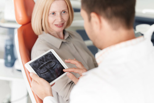 Older woman discussing dental implants with her dentist at East Portland Dentistry in Portland, OR